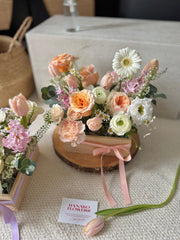  floral arrangement with a pink ribbon on a textured surface, featuring the brand 'Hanako Flowers'.
