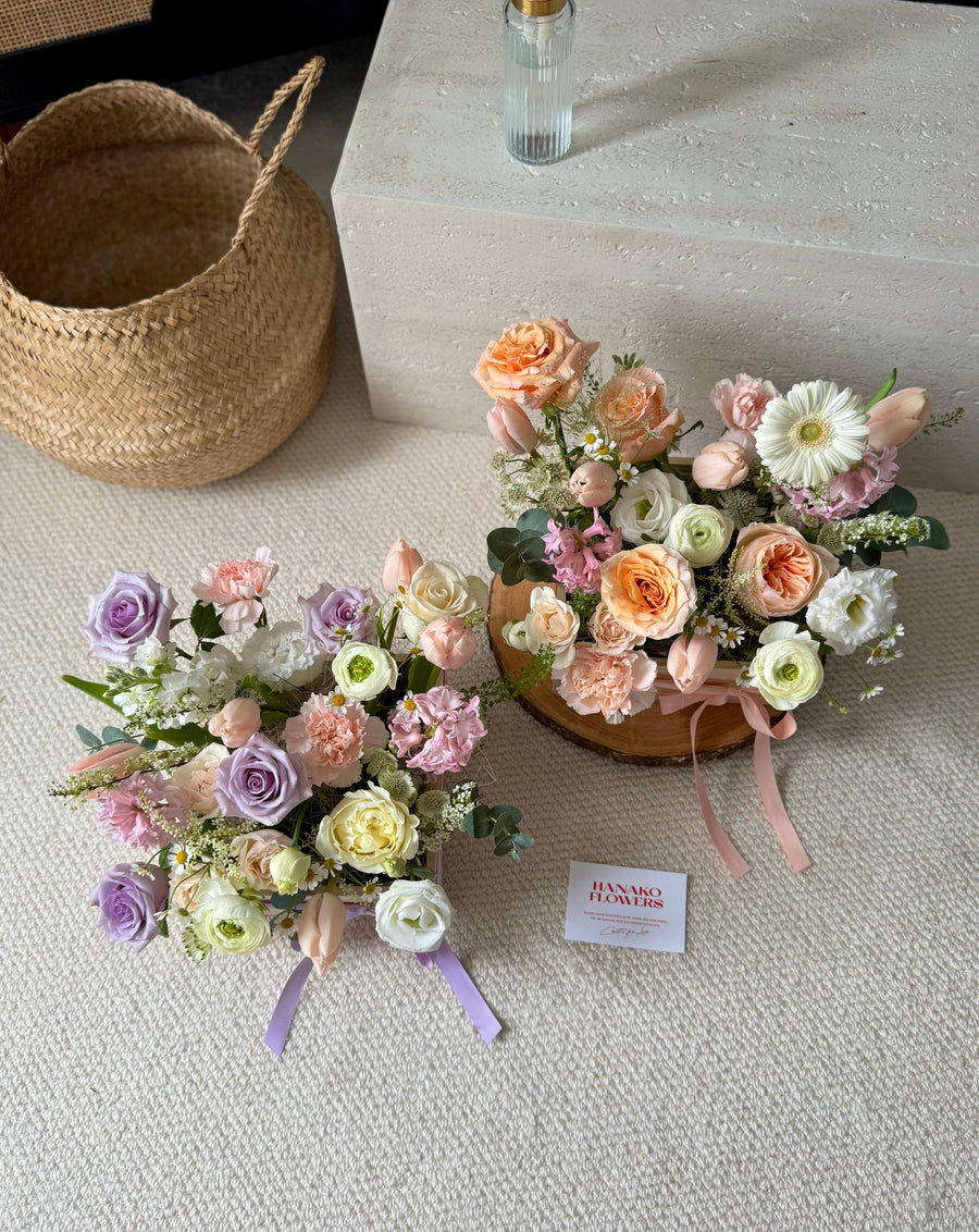 Two floral arrangements on a textured surface with a woven basket in the background.