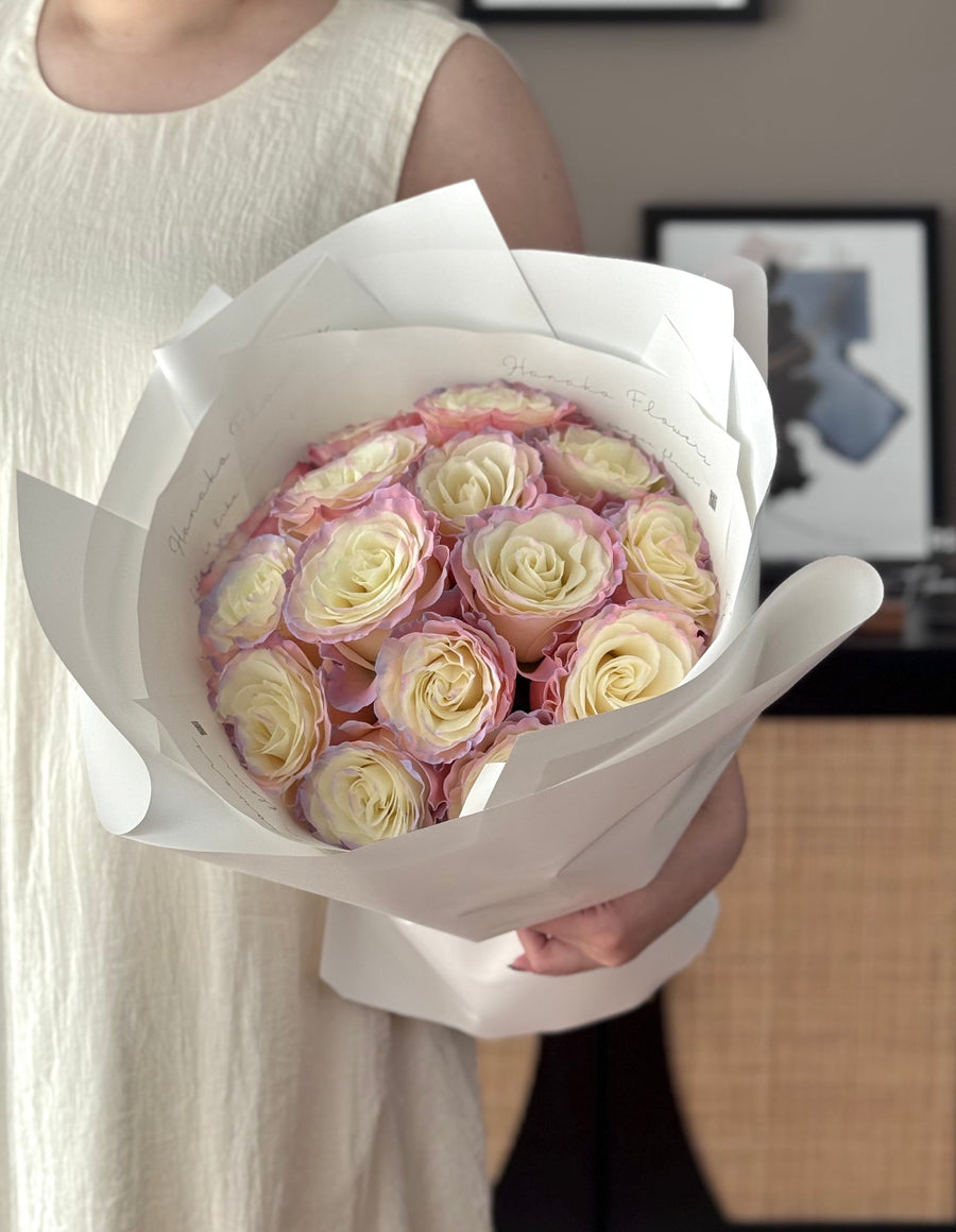 Bouquet of pink and white roses held by a person in a neutral setting
