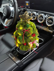 Decorative Christmas tree in a car's center console with a star on top.