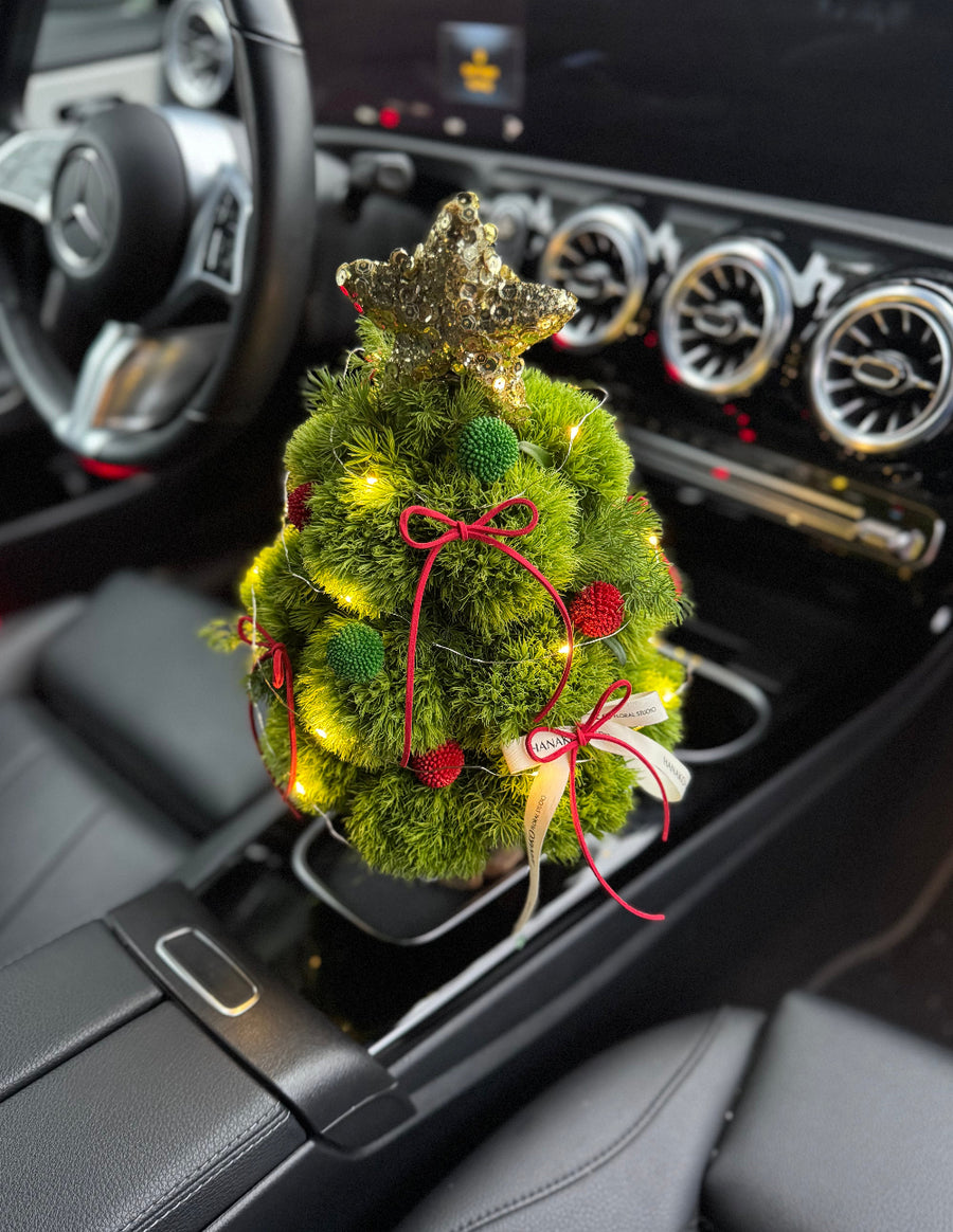 Decorative Christmas tree in a car's center console with a star on top.