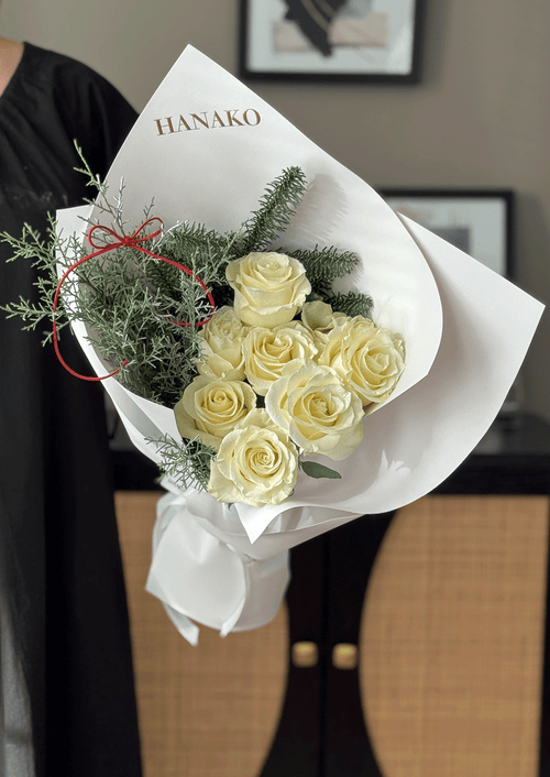 Bouquet of white roses with greenery wrapped in white paper, brand 'HANAKO' visible.