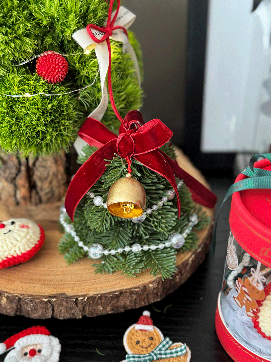 Decorative Christmas scene with a small tree, ornaments, and a gingerbread man figurine on a dark surface.