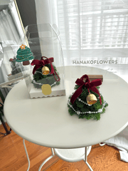 Decorative Christmas tree ornaments on a white table with 'HANAKOFLOWERS' branding.