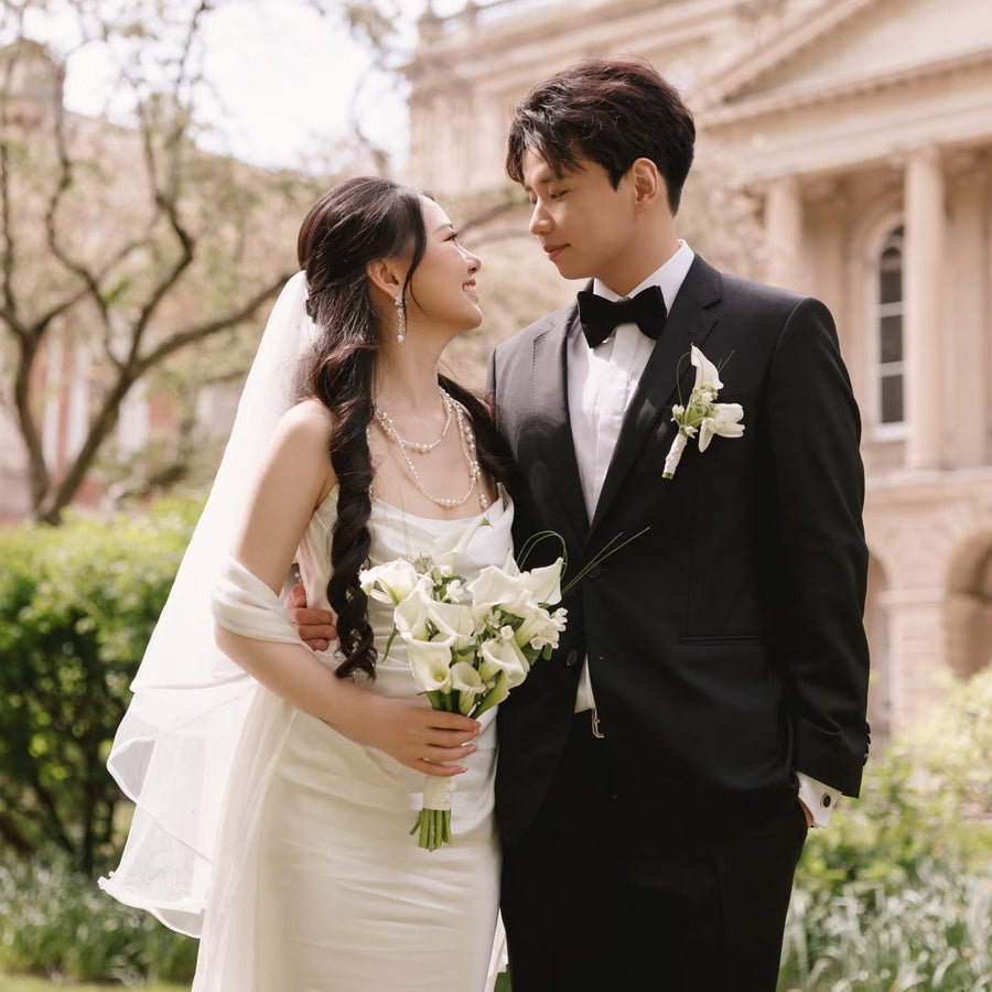 Wedding couple standing outdoors with a building in the background